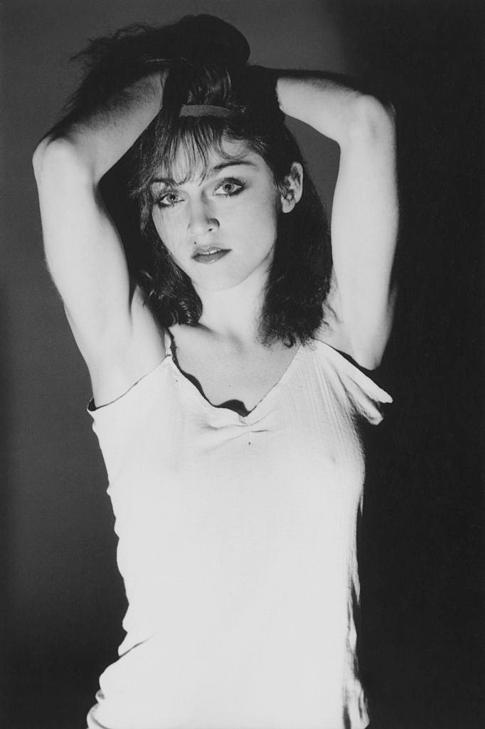 #11 Madonna in a cotton camisole, holding her dark, shoulder-length crimped hair, 1978.