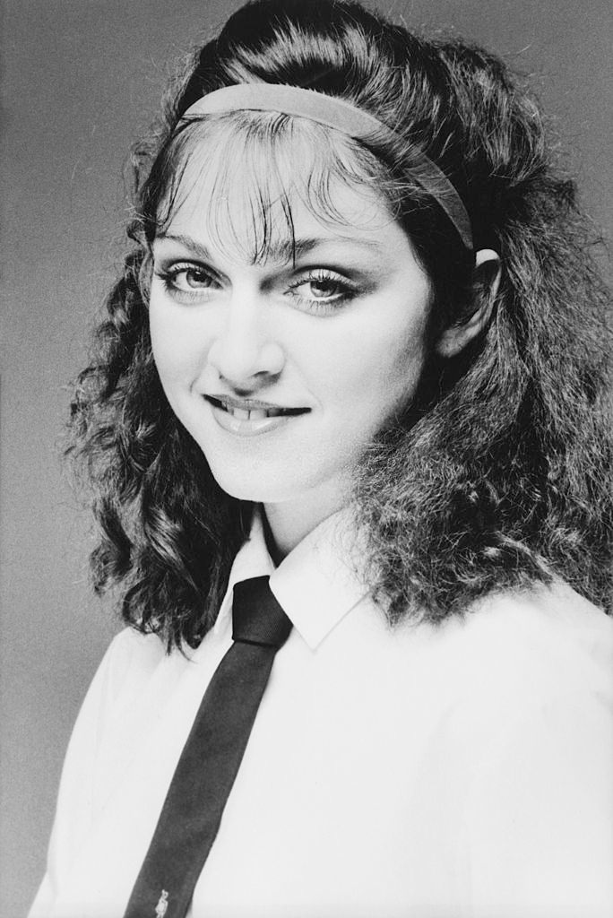 #12 Madonna smiling while wearing a white cotton shirt with a dark tie, 1978.