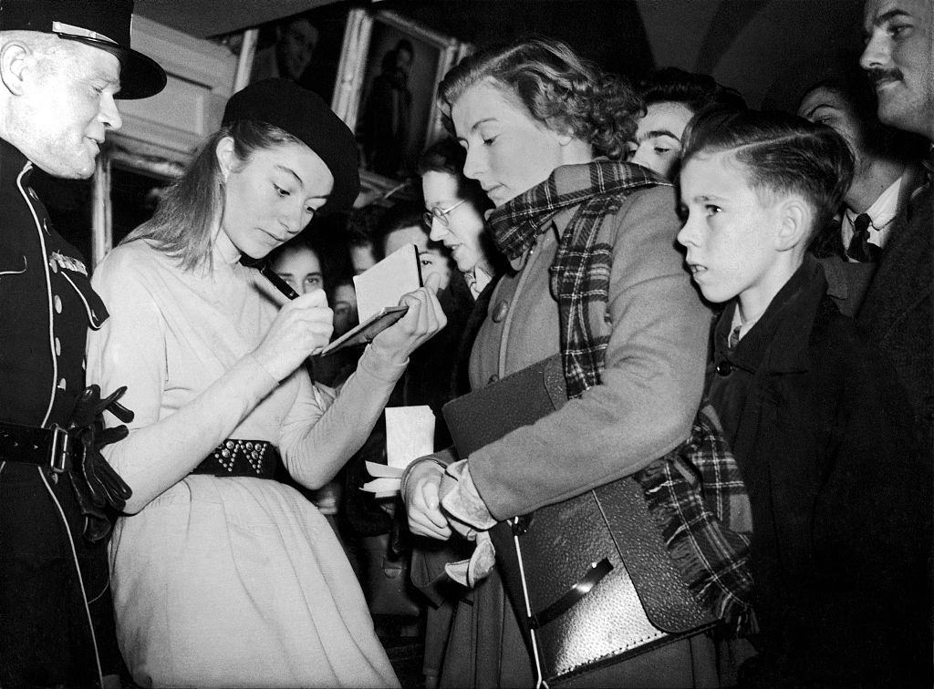 #45 Anouk Aimée signing an autograph, circa 1950.
