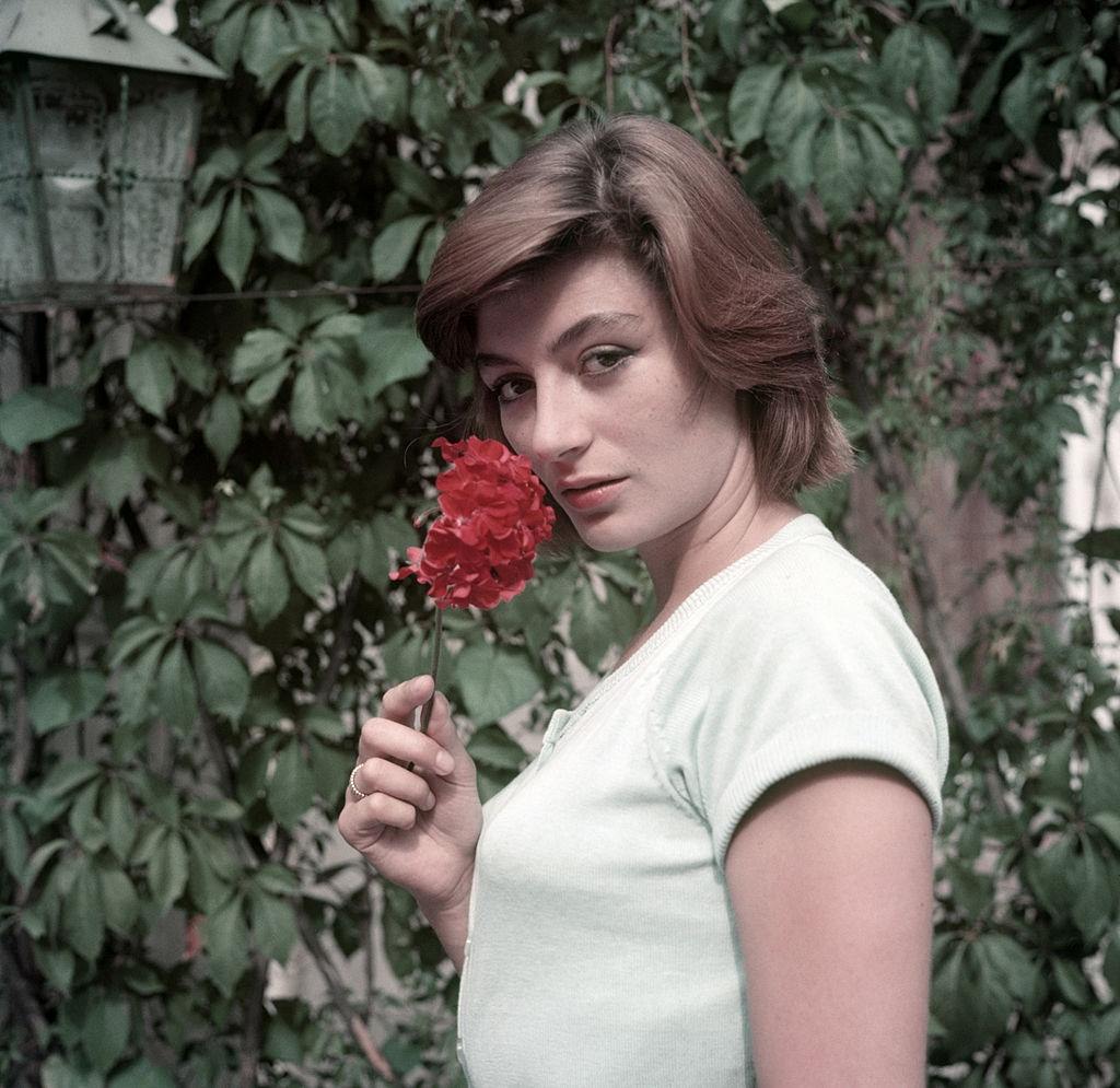 #1 Anouk Aimée poses takes a flower in her hand, 1955.