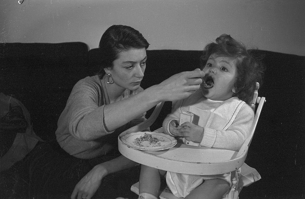 #48 Anouk Aimée feeding her daughter, 1955.