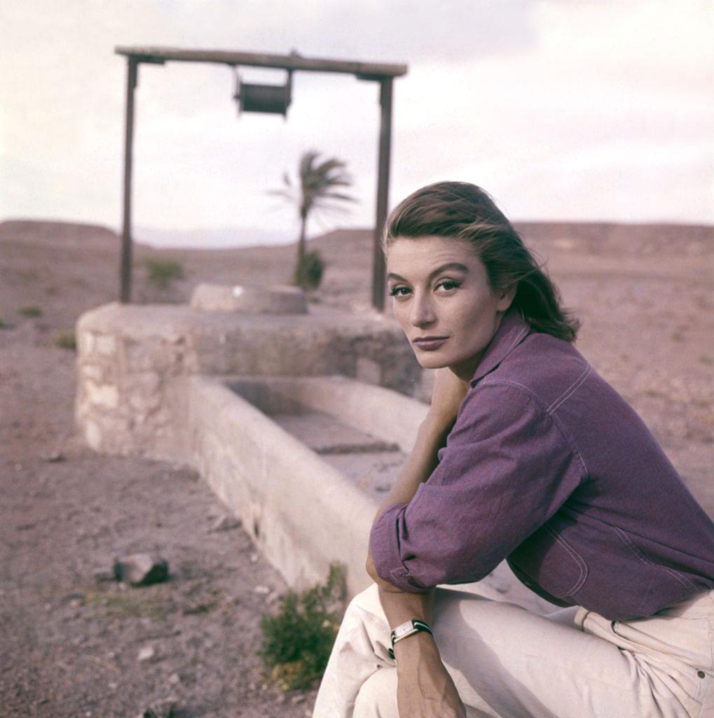 #23 Anouk Aimée sitting on a water-hole in the desert, 1960s.