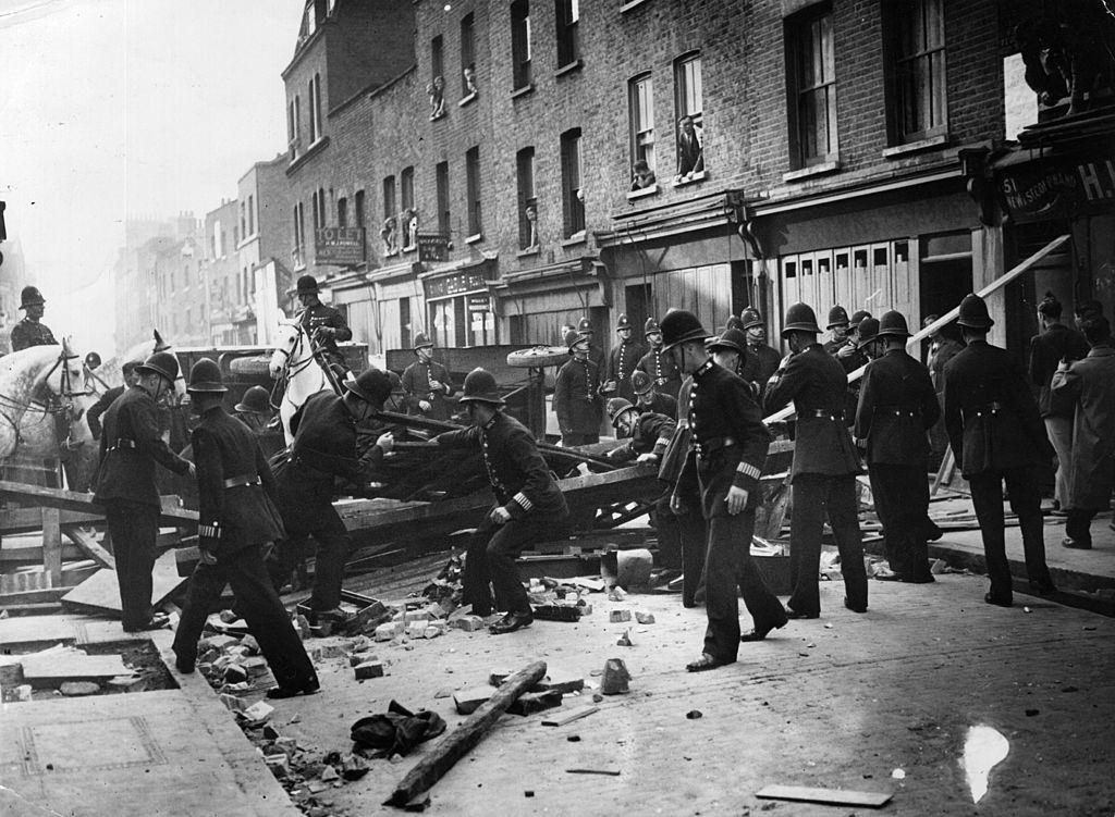 #5 British policemen dismantle a barrier near Mark Lane, London, to make way for a march by supporters of the leader of the British Union of Fascists Oswald Mosley.