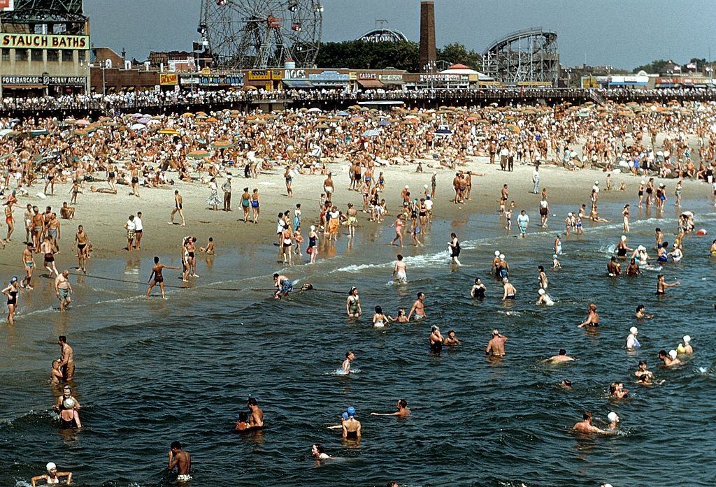 #24 Coney Island Boardwalk with sunbathers and swimmers on the beach, 1948.