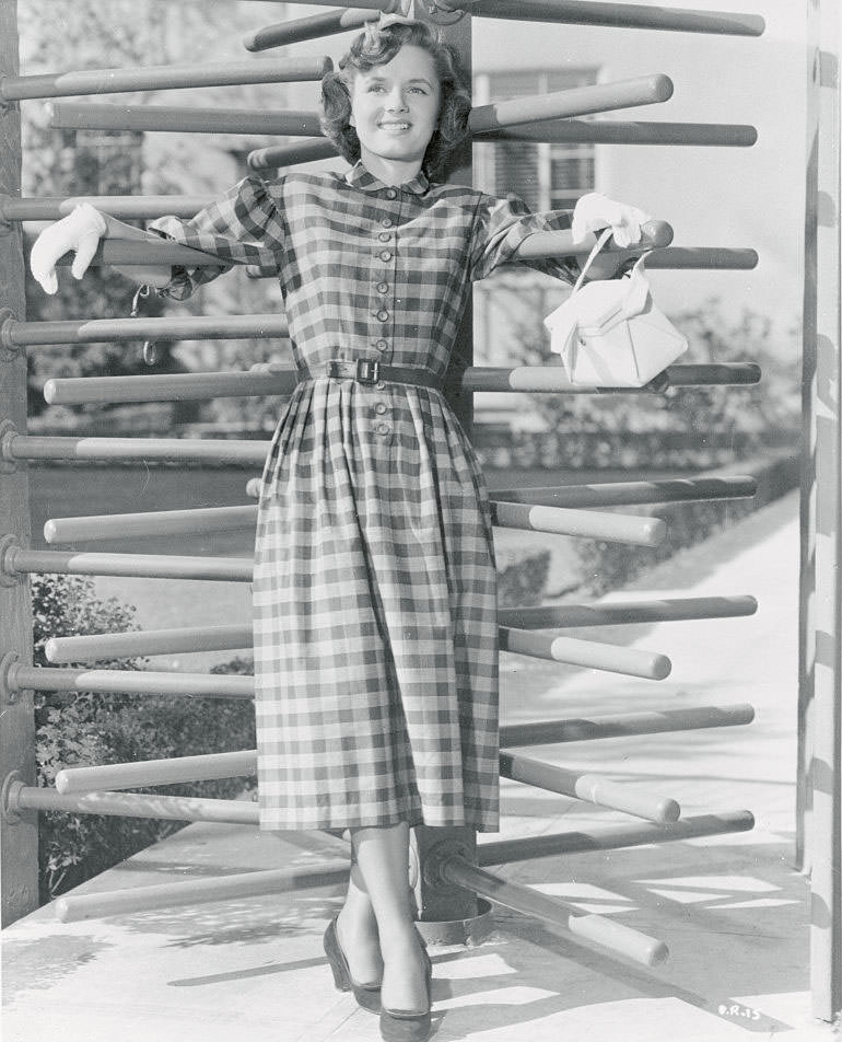 #36 Debbie Reynolds wears a button-front plaid cotton dress with demure, rounded collar and three-quarter sleeves, 1950.