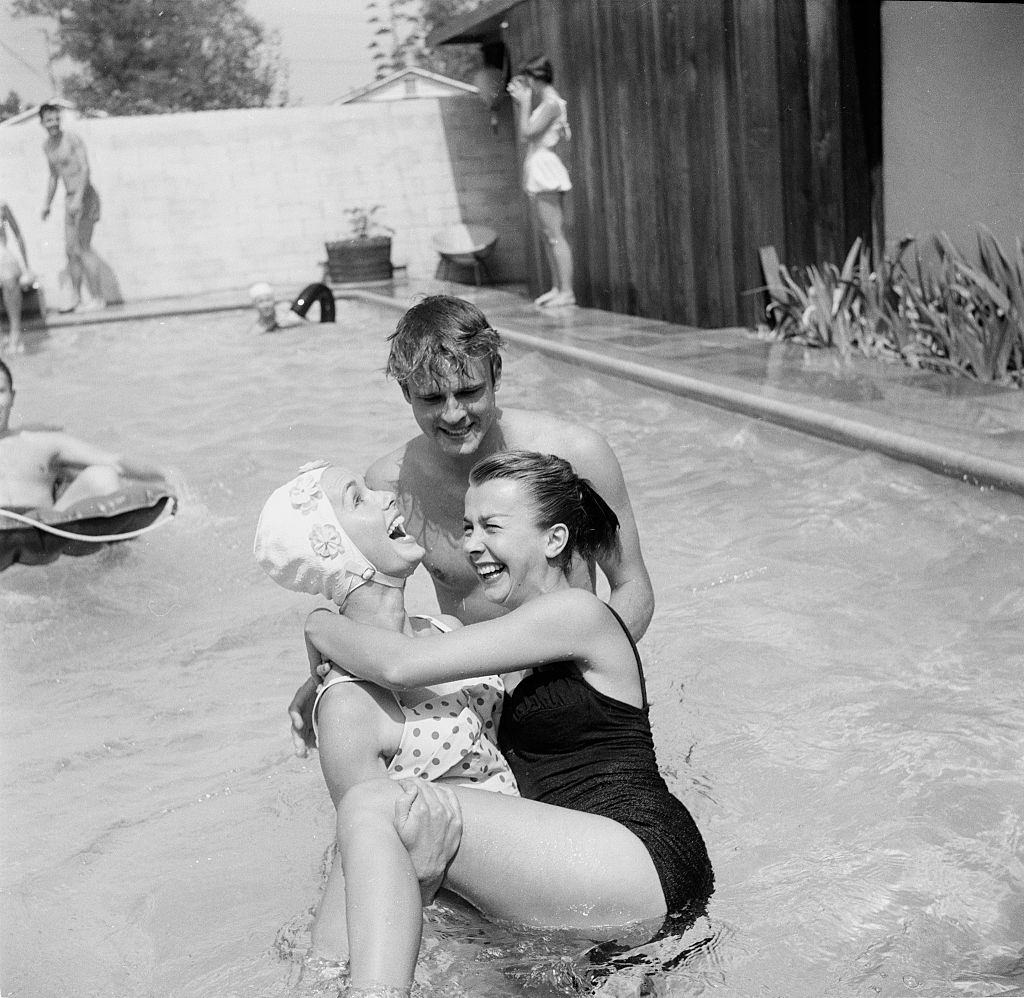 #67 Debbie Reynolds entertains guest at her pool party, 1955.