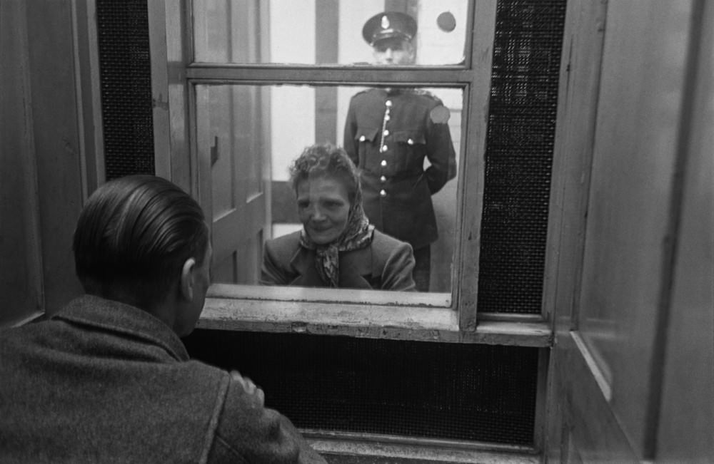 #10 Prison officer Davidson watches as a prisoner talks to a visitor at Strangeways Prison.