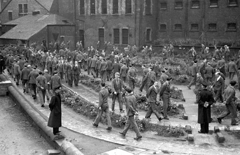 #3 Prison officers watching over prisoners as they take their daily hour of outdoor exercise at Strangeways Prison.