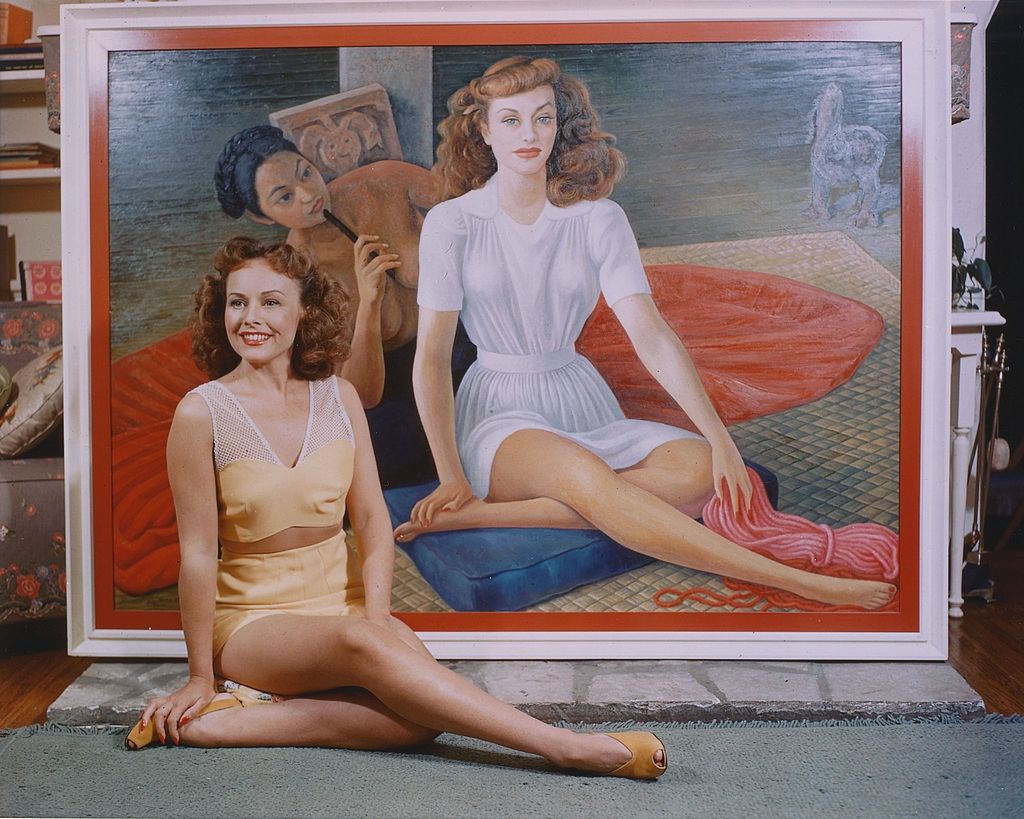 #71 Paulette Goddard sitting on the floor alongside a portrait of herself, painted by the Mexican artist, Diego Rivera, 1940.