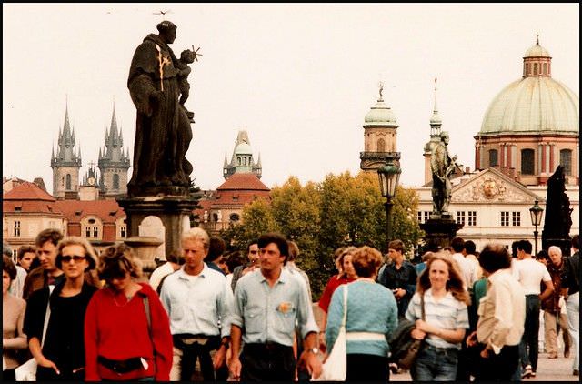 #46 Students and shoppers cross the Charles Bridge at lunchtime. St Nicholas church is in the background