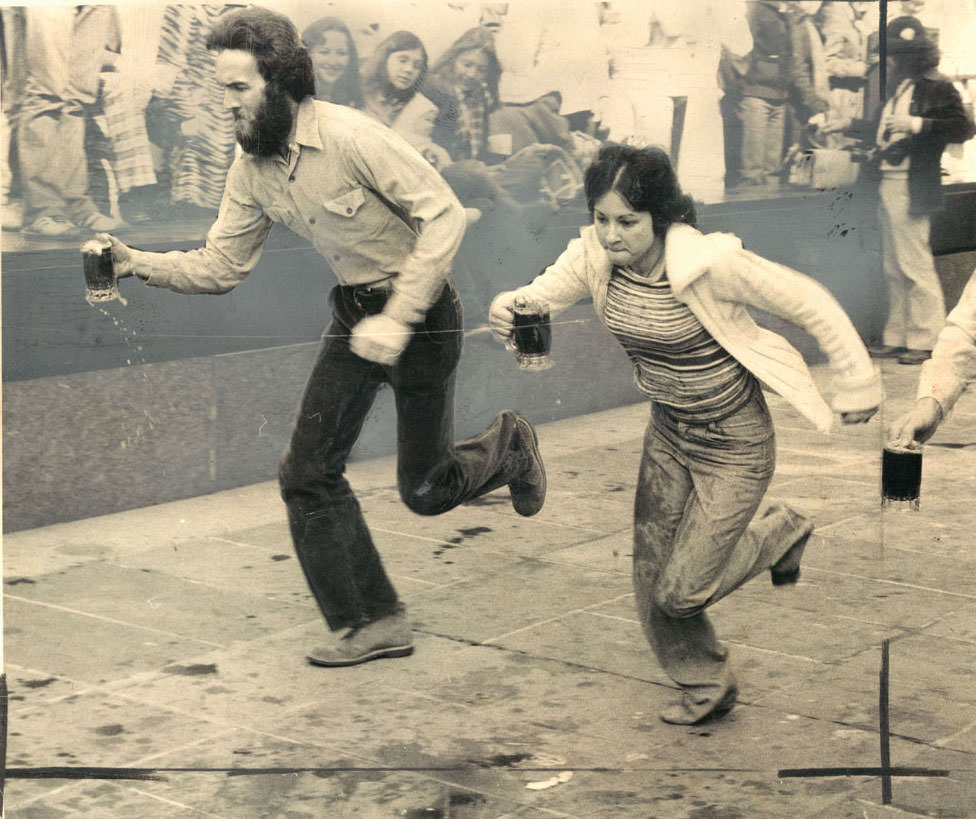 #12 Bernie Keenan (with beard) defeats Casey Cole in Hopkins Plaza on the way to victory in St. Patrick’s Day Beer Mug Race. March, 1979.