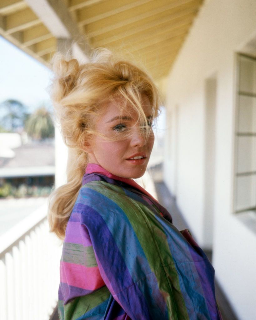 #52 Tuesday Weld, in a striped top, as she poses on a windy balcony, 1960s.