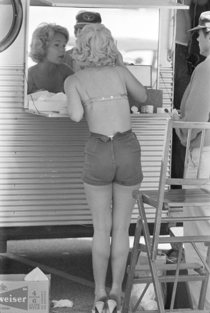 #56 Tuesday Weld looks into a mirror as her make-up artist stands beside her during the production of her film ‘Soldier in the Rain’, 1963.
