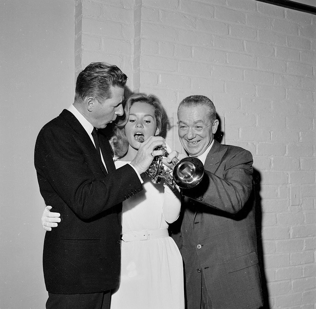 #24 Tuesday Weld with Danny Kaye as she pretends to play a trumpet during an event in Los Angeles, 1958.