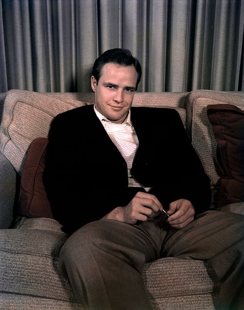 #9 Marlon Brando sitting on a couch and smiling, 1950.