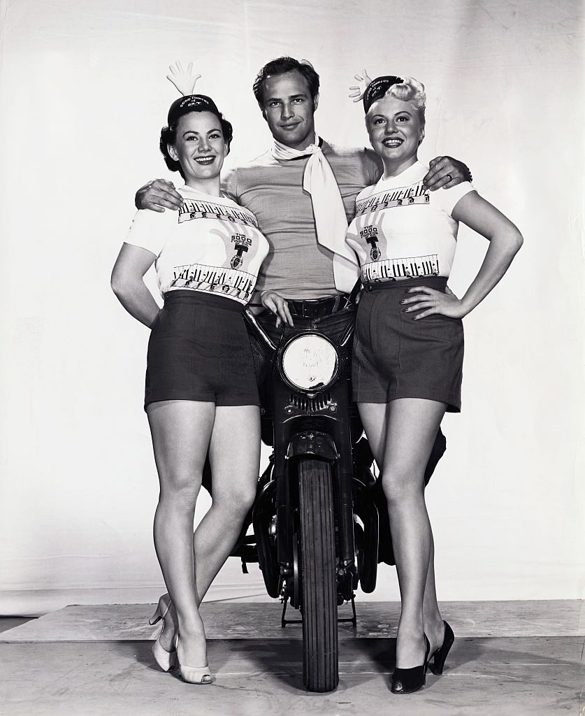 #73 Marlon Brando on Motorcycle and Posing with young Women, 1955.