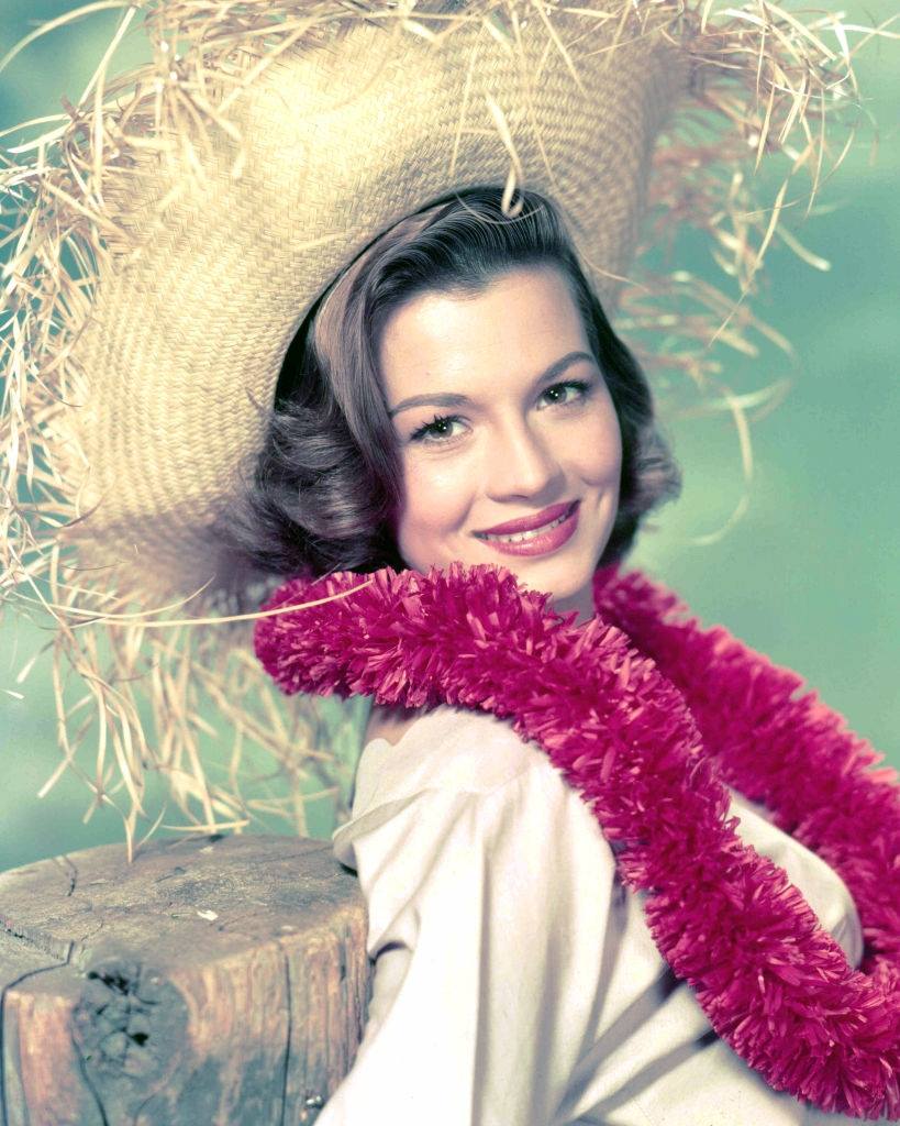 #39 Angie Dickinson wearing a pink garland and a straw hat, 1955.