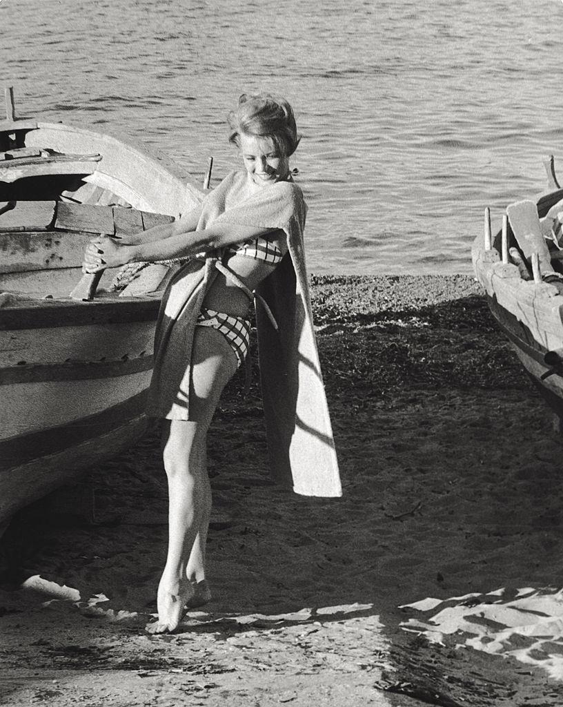#55 Angie Dickinson posing on the beach next to a rowing boat, 1961.