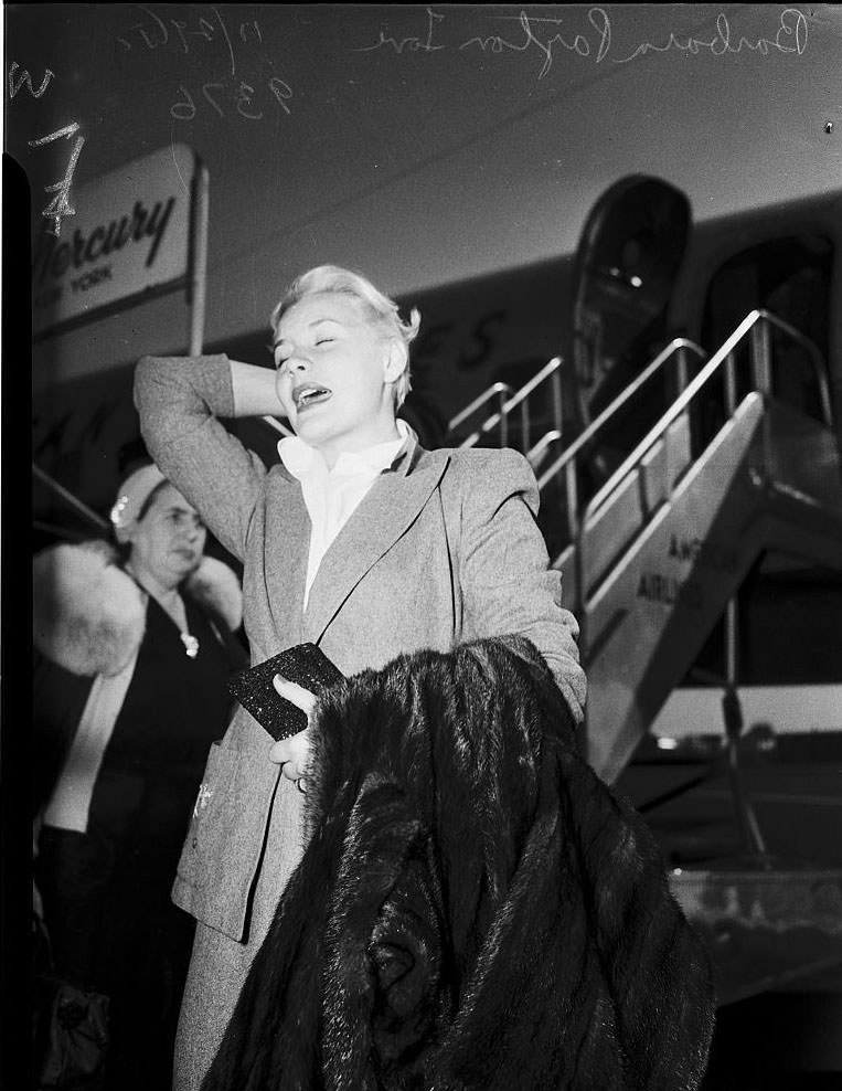 #27 Barbara Payton waiting for the arrival of Franchot Tone, 1951.