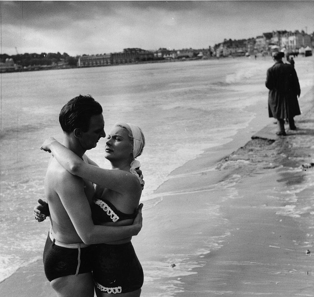 #45 Barbara Payton with Stephen Murray for a scene in a British film, ‘The Four Sided Triangle’ being shot at Weymouth in Dorset, 1952.