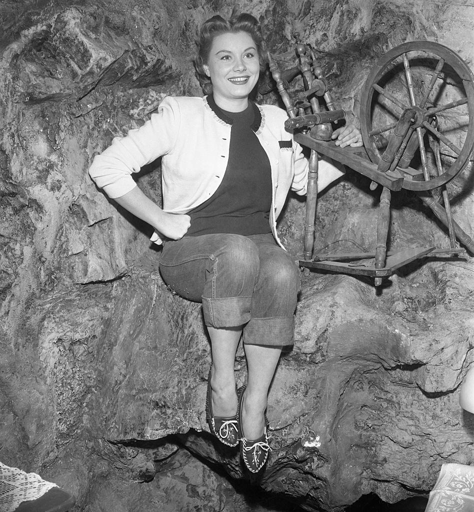 #50 Barbara Payton poses by a spinning wheel on the set of the movie, 1952.