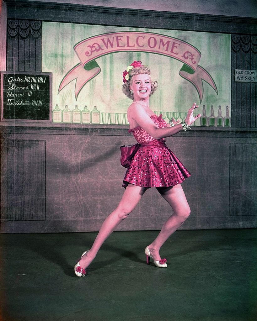 #35 Betty Grable wearing a short red dress as she holds a dance pose, 1940.