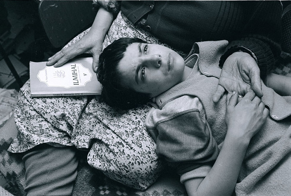 Mirza Mangajic, a 10-year-old Muslim boy, lays his head in his grandmother’s lap as he prays with her.