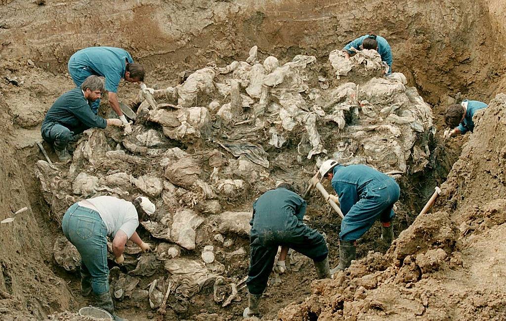 #9 Forensic experts from the International war crimes tribunal in the Hague works on a pile of partly decomposed bodies, 24 July 1996 found in a mass grave in the village of Pilica some 300 km northeast of Sarajevo.