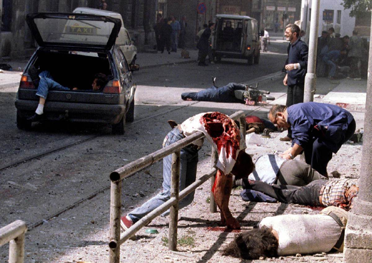 #22 Dead and wounded people lie scattered outside Sarajevo’s indoor market after a mortar shell exploded outside the entrance to the building, on August 28, 1995.