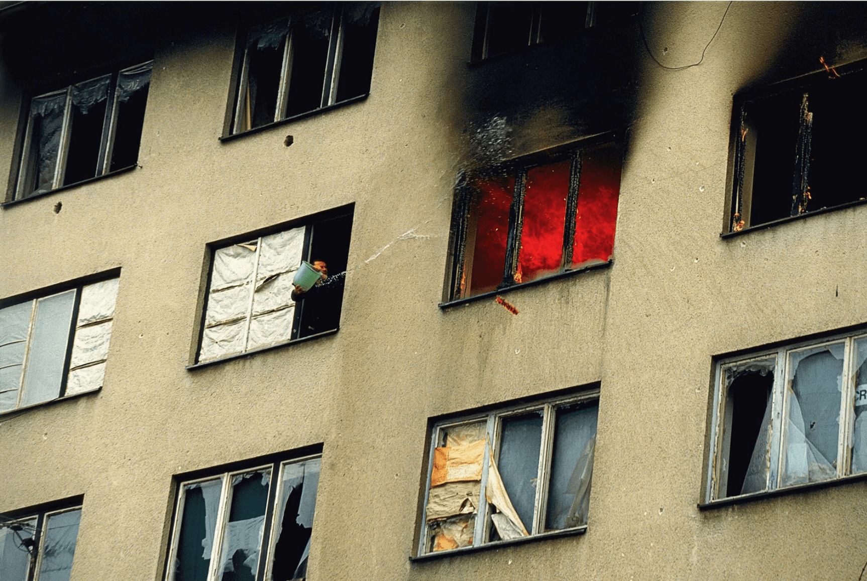 #36 A Serb man attempts to put out a fire that was caused by Serb arsonists in the Sarajevo suburb Grbavica, Bosnia, 1996.