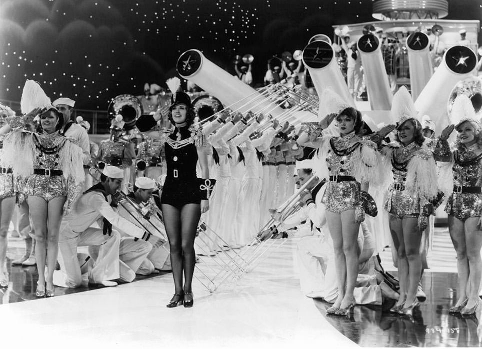 #35 Eleanor Powell gives a salute with many other performers in a scene from the film ‘Born To Dance’, 1936.