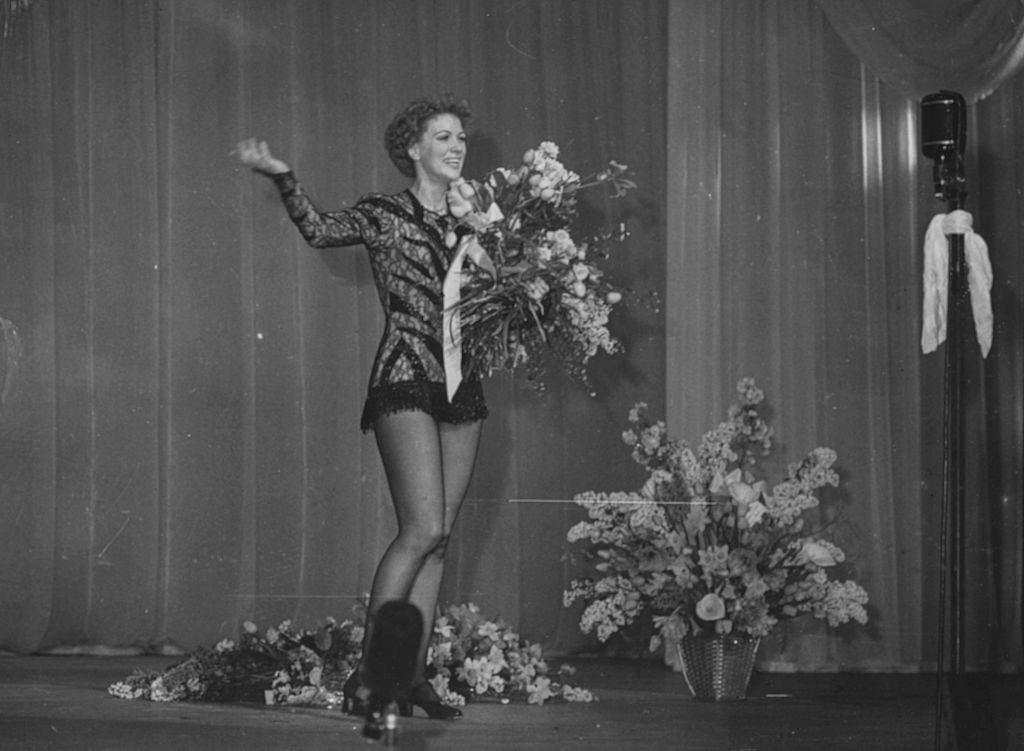 #69 Eleanor Powell holding a bouquet of flowers following a performance on the stage, March 21st 1949.