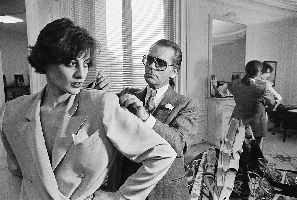#47 Karl Lagerfeld fits one of his designs on top model Ines de la Fressange at Chloe’s Paris studio.