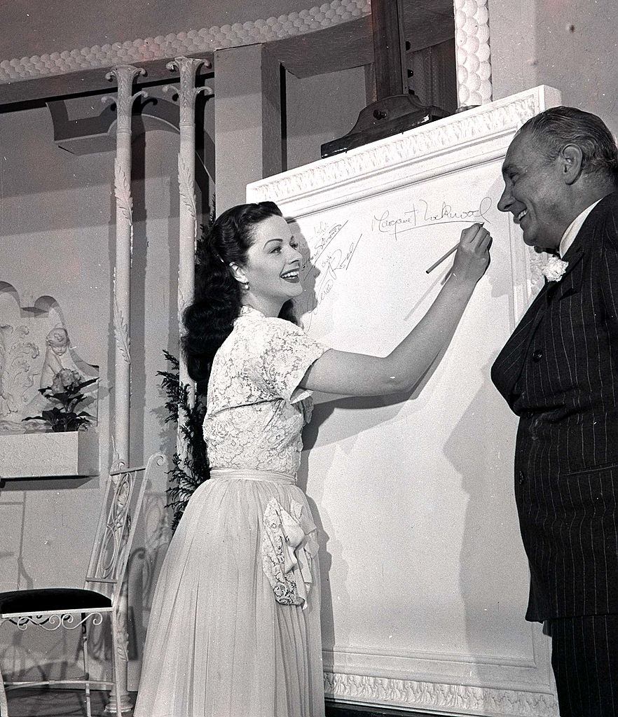 #26 Margaret Lockwood as she signs the “Roll of Fame” watched by Henry Edwards, 1947.