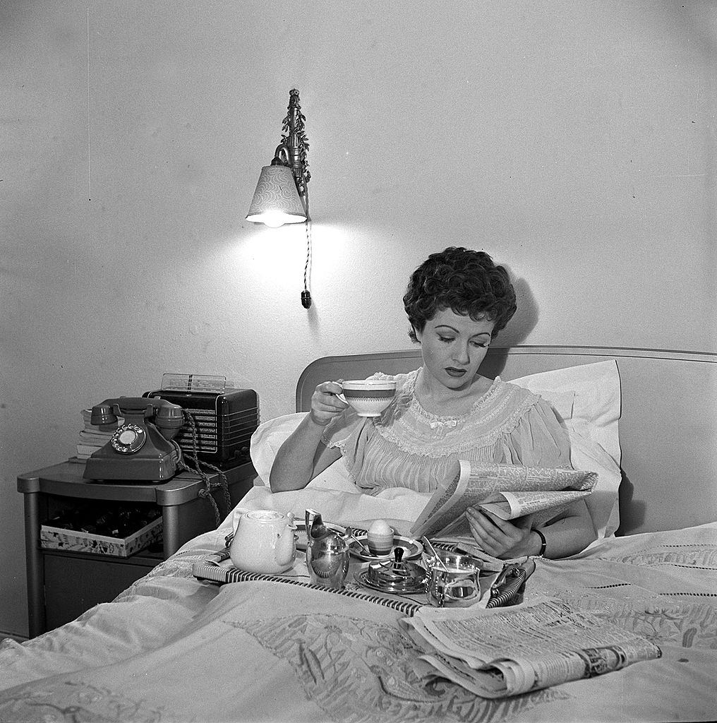 #63 Margaret Lockwood is pictured reading the newspapers as she enjoys breakfast in bed, 1950