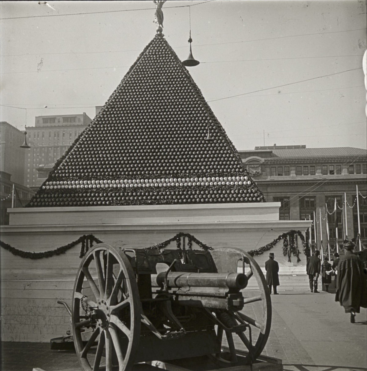 #8 This is quite a visual–a pyramid built of what appears to be artillery shells, with a gun in the foreground.