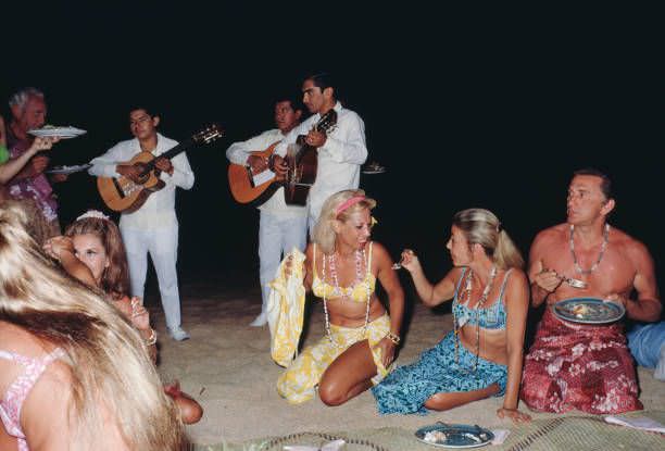 #12 American singer Dinah Shore (center) and actor Kirk Douglas (far right) at a beach party in Acapulco, Mexico, January 1968