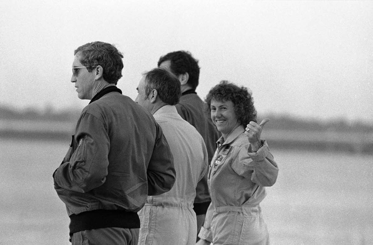 #8 Christa McAuliffe gives a thumbs-up as she prepares for a test flight at Kennedy Space Center. Jan. 24, 1986.