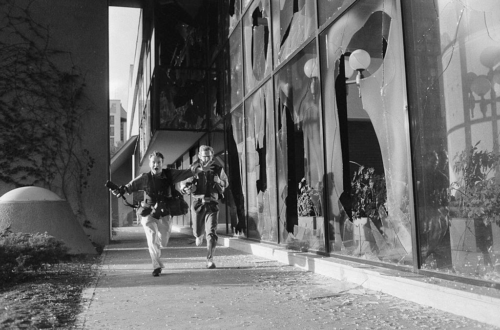 #16 Photographers Paul Lowe and David Turnley run for cover beside the Holiday Inn hotel which was home to the media during the war, July 1992.