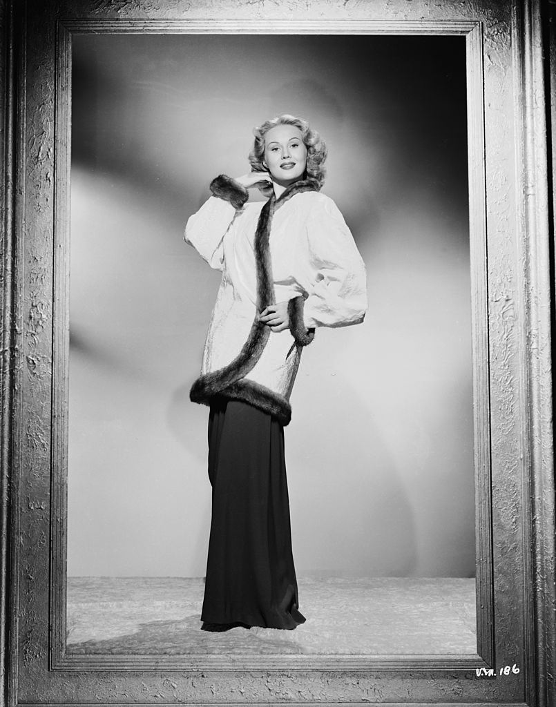 #33 Virginia Mayo wearing a fur-trimmed jacket and loose-fitting trousers, 1950.