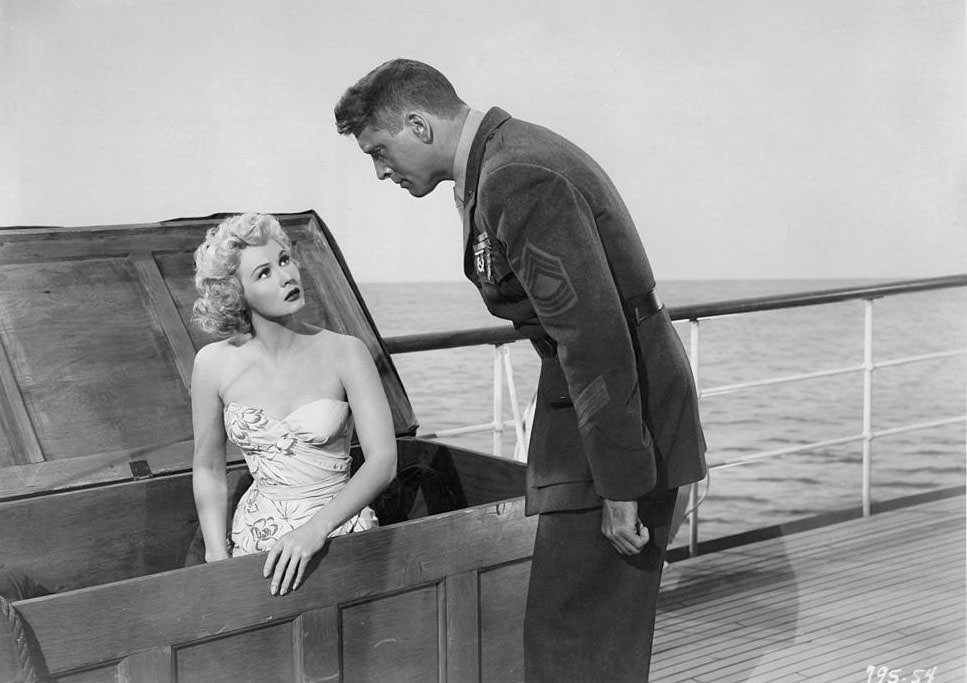 #41 Virginia Mayo sitting in crate as Burt Lancaster looks over her in a scene from the film ‘South Sea Woman’, 1953.