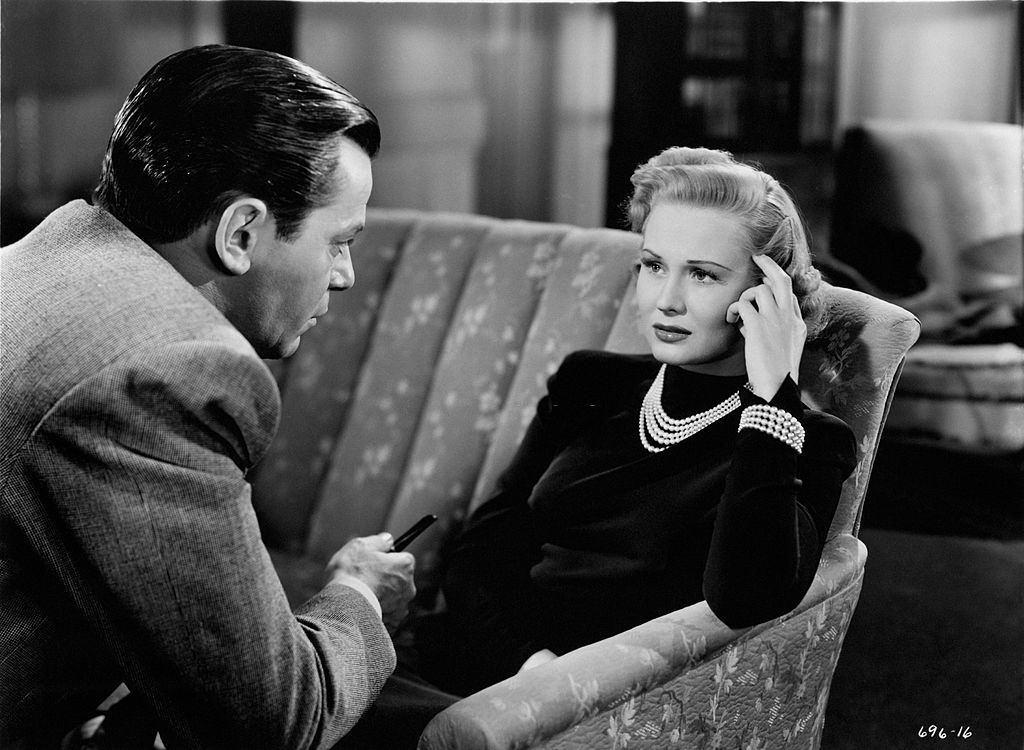#64 Virginia Mayo seated on the sofa, looking into eyes of Robert Hutton in a scene from the movie ‘Smart Girls Don’t Talk’, 1948.