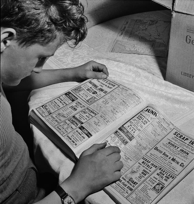 #5 Boy is looking up junk dealers in the telephone directory, wants junk dealer pick up the scrap which he collected stored in his cellar, Washington, D.C., May 1942