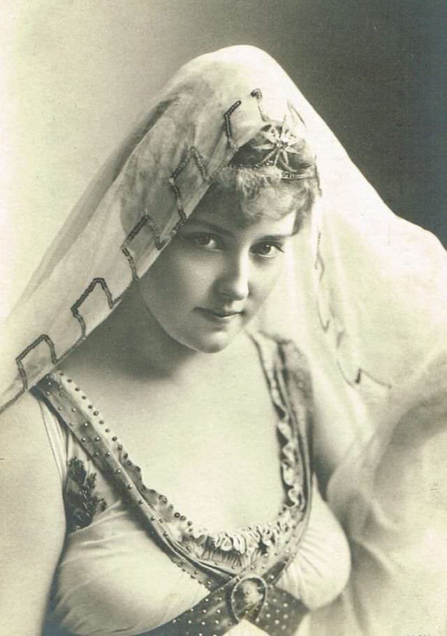#22 Lillian Russell wearing a lace and crochet princess-style gown, accessorized with an aigrette feather-trimmed hat, 1905.