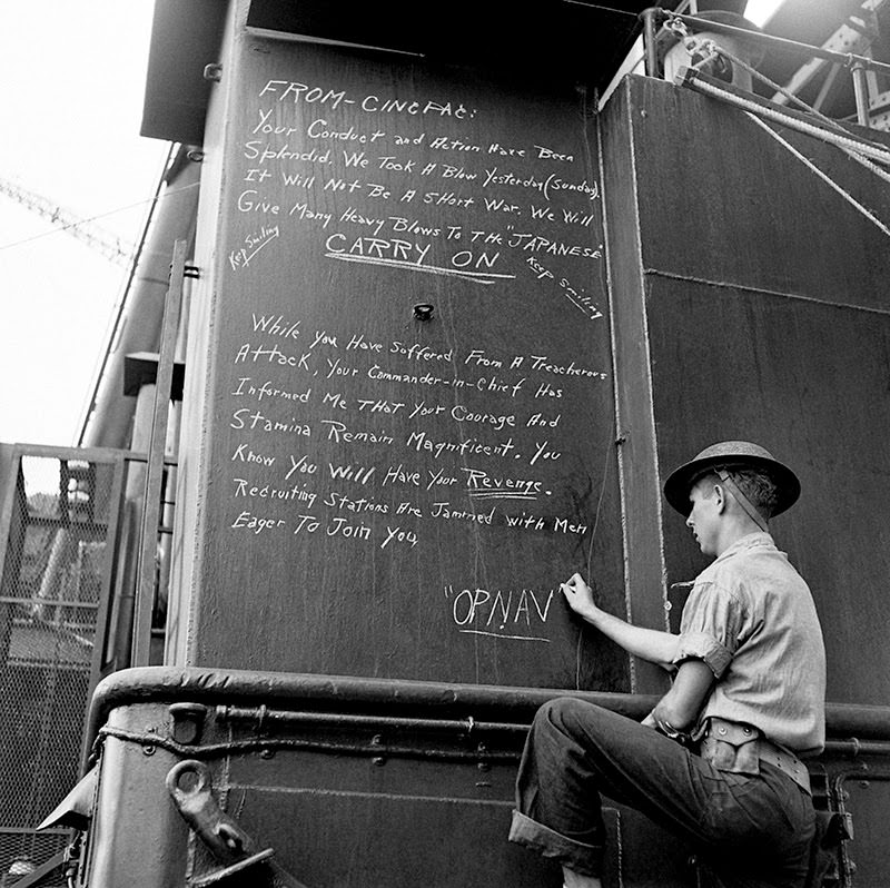 #19 A sailor chalks a message to America’s fighting men from the Office of the Chief of Naval Operations on a warship at Pearl Harbor.