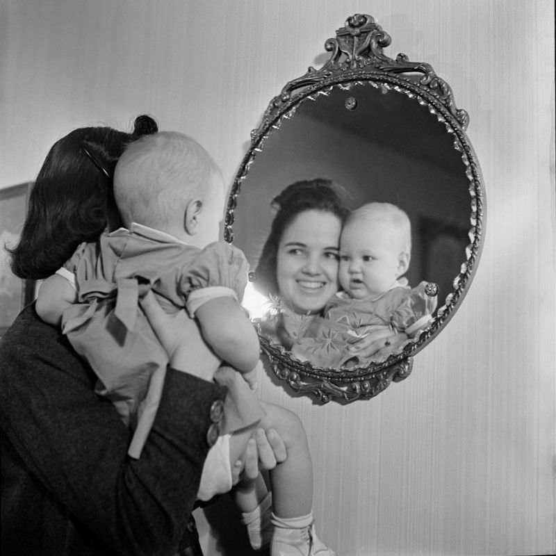 #1 A woman holding an unidentified infant girl in front of a mirror