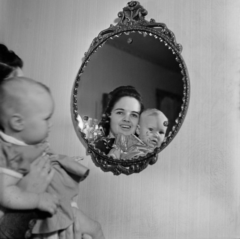 #2 A woman holding woman holding an unidentified infant girl in front of a mirror