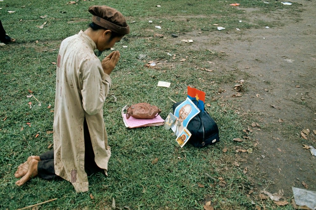 #31 A Vietnamese man prays in front of a portrait of Ho Chi Minh after the Fall of Saigon.