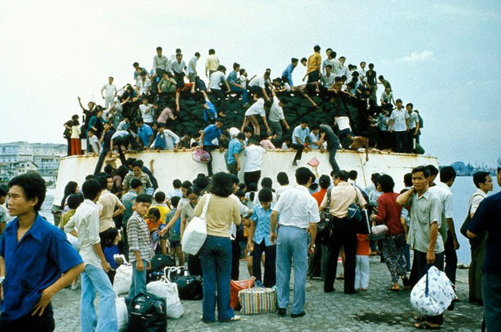 #57 South Vietnamese clamber aboard barges in the port of Saigon in an attempt to escape from advancing North Vietnamese troops on the day of the Fall of Saigon that ended the Vietnam War