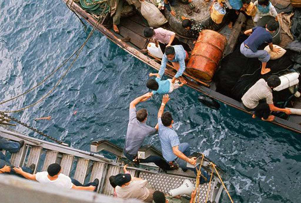#13 Crewmen of the amphibious cargo ship U.S.S. Durham (LKA-114) take Vietnamese refugees aboard from a small craft.